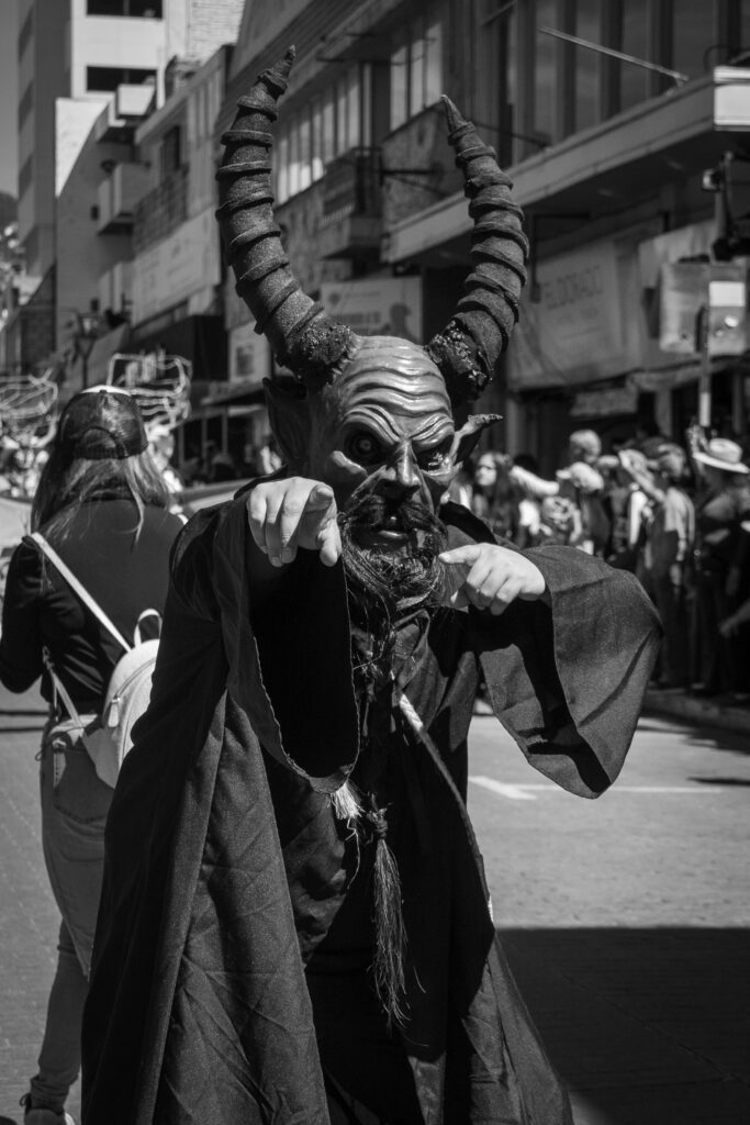 Black and white photo of a masked figure in a carnival parade in Hidalgo, Mexico.