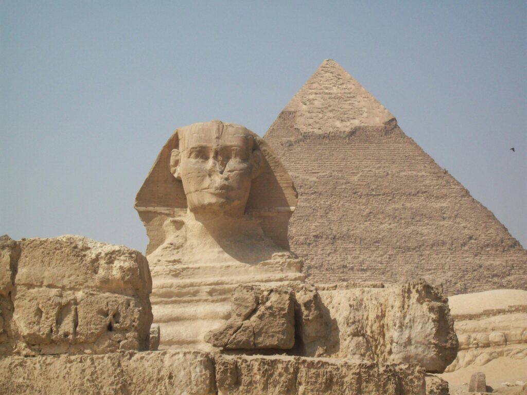 View of the Great Sphinx and Pyramid in Giza, Egypt, under a clear sky.