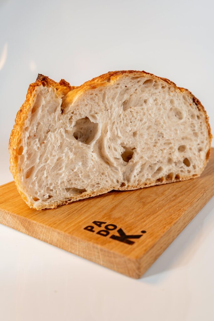 Close-up of a slice of artisanal sourdough bread placed on a wooden board.