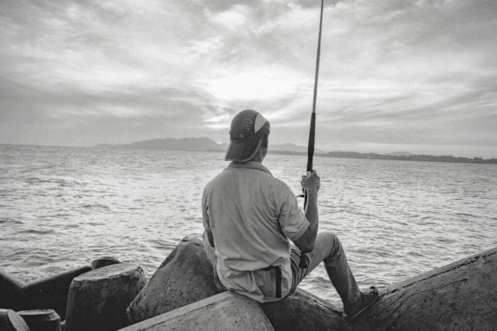 A peaceful scene of a man fishing at the seaside during dusk.