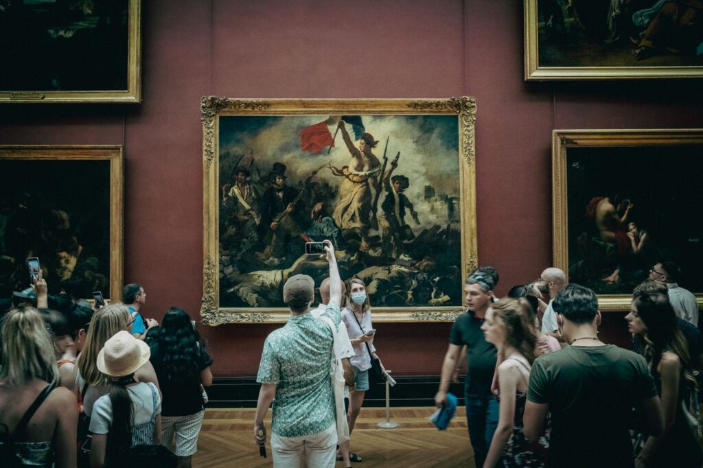 Crowd admires and photographs iconic art in the Louvre Museum, Paris.